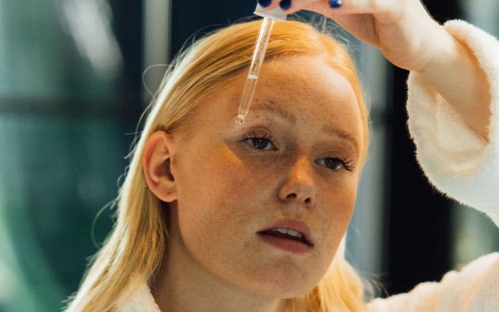 Mujer aplicándose sérum de retinol con pipeta